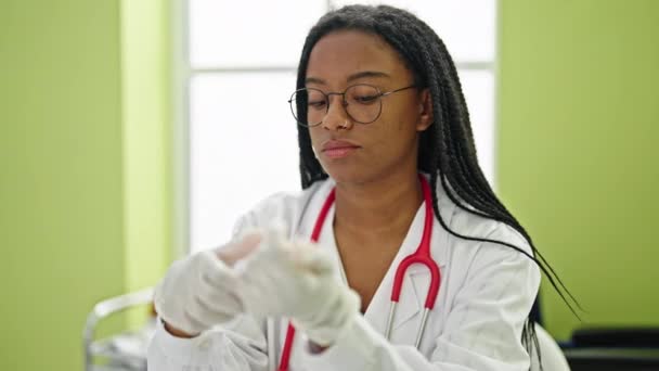 Африканская Американка Доктор Улыбается Уверенно Надевая Перчатки Клинике — стоковое видео