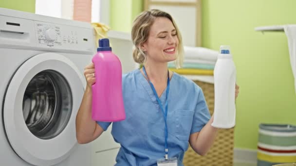 年轻的金发女士在洗衣房选择洗涤剂瓶子做大拇指举动作 — 图库视频影像