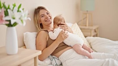 Anne ve kızı yatakta uzanıp yatak odasında öpüşüyor.