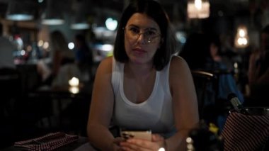 Genç ve güzel İspanyol kadın restoranda masanın üzerinde akıllı telefon kullanıyor.