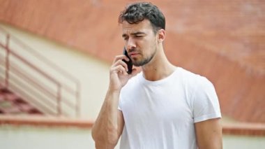 Genç İspanyol adam gülümsüyor. Kendine güveniyor. Sokakta akıllı telefondan konuşuyor.