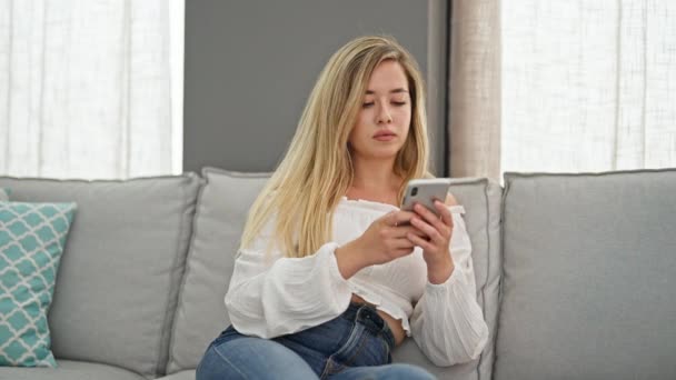 Young Blonde Woman Using Smartphone Doing Gesture Home — Stok video
