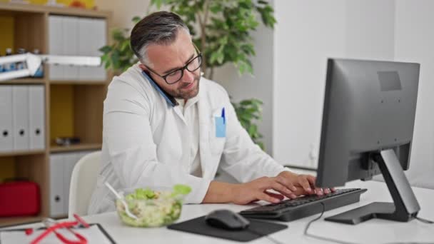 Grey Haired Man Doctor Eating Salad Talking Smartphone Clinic — Stock Video