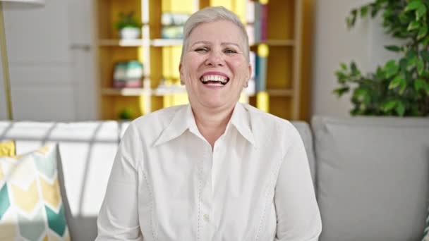 Mujer Pelo Gris Mediana Edad Sonriendo Confiada Sentada Sofá Casa — Vídeo de stock
