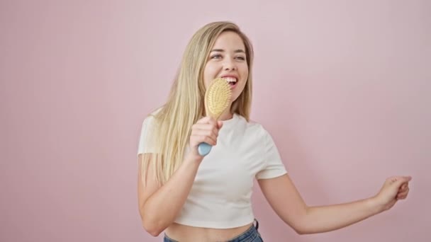 Молодая Блондинка Поет Песню Используя Расческу Качестве Микрофона Изолированном Розовом — стоковое видео