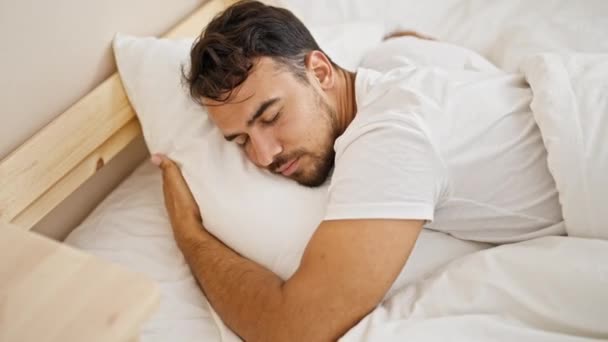 寝室で寝ているベッドに横たわる枕を抱擁する若いヒスパニックの男 — ストック動画