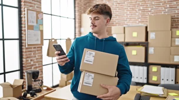 Młody Latynoski Człowiek Commerce Pracownik Pomocą Smartfona Trzymając Pakiety Biurze — Wideo stockowe