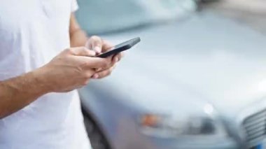 Genç İspanyol adam akıllı telefon kullanıyor. Arabasının yanında bekliyor.