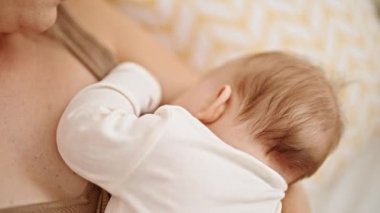 Anne ve kızı yatak odasında bebek emziriyorlar.