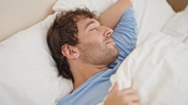 Genç İspanyol adam yatakta uzanıp yatak odasında uyuyor.