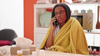 Afro-Amerikalı kadın, yemek odasında hasta olduğu için akıllı telefondan tıbbi danışmanlık alıyor.