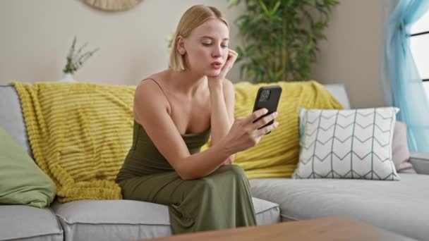 Mujer Rubia Joven Usando Teléfono Inteligente Buscando Molesto Casa — Vídeo de stock