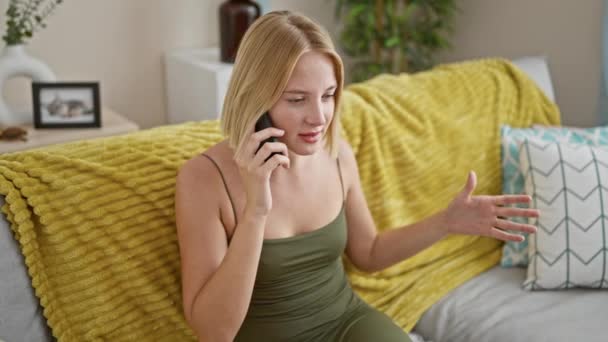 Молодая Блондинка Говорит Телефону Сидя Диване Споря Дома — стоковое видео