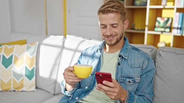 Młody Biały Mężczyzna Pomocą Smartfona Picie Kawy Domu — Wideo stockowe