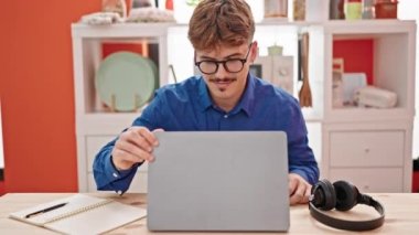 Genç İspanyol adam yemek odasında dizüstü bilgisayarı açıp masada dans ediyor.