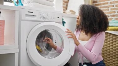Kirli gömlekli, kirli çamaşırlarını yıkayan Afro-Amerikalı kadın çamaşırhaneye üzgün bakıyor.