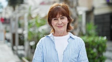 Orta yaşlı kadın gülümsüyor. Kendine güveni tam. Başparmağıyla sokakları imzalıyor.