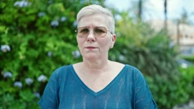 Orta yaşlı, gri saçlı, yüzünde ciddi bir ifadeyle 