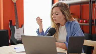 Müzik stüdyosundaki bir radyo programında genç sarışın muhabir.