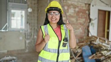 Genç Çinli mimar, şantiyede baş parmak hareketi yaparak gülümsüyor.