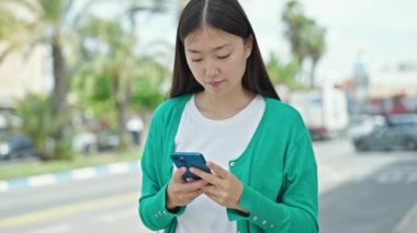 Genç Çinli kadın parkta el yapımı akıllı telefonla jesti durduruyor.