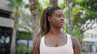 Afro-Amerikalı kadın parkta kendinden emin bir şekilde gülümsüyor.