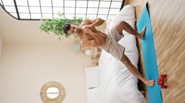 Genç İspanyol adam yatak odasında bacak egzersizi yapıyor.