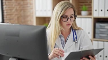 Klinikte bilgisayar okuyan genç sarışın kadın doktor.