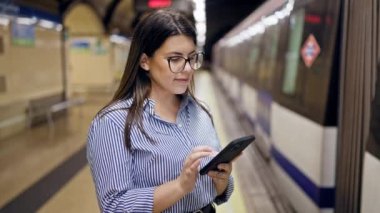 Madrid metro istasyonunda akıllı telefon kullanan güzel İspanyol bir kadın metroda bekliyor.