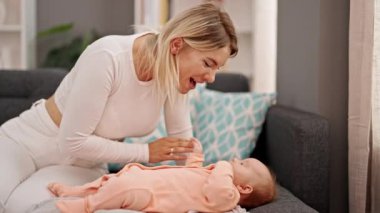 Anne ve kızı kanepede uzanmış gülümsüyor.