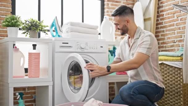 Ung Latinamerikansk Man Ler Självsäker Tvätt Kläder Tvättstuga — Stockvideo