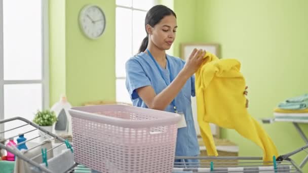 アフリカ系アメリカ人女性 プロのクリーナー 洗濯室で服のラインに掛かる服 — ストック動画