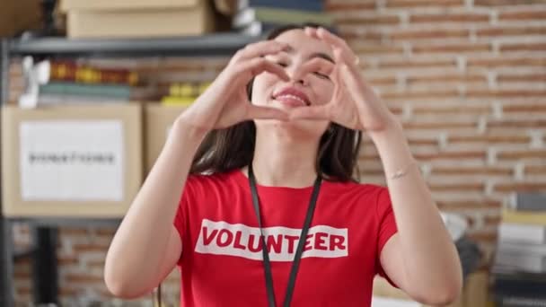 Молодая Красивая Латиноамериканка Волонтер Делает Сердечный Жест Улыбаясь Благотворительном Центре — стоковое видео