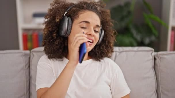 年轻美丽的惊慌失措的女人在家里用智能手机听着音乐唱歌 — 图库视频影像