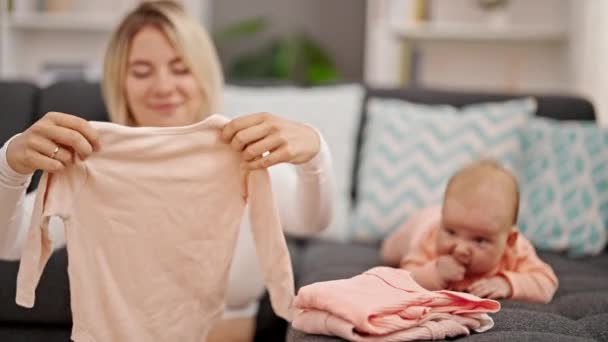Anne Kızı Ellerinde Bebek Kıyafetleriyle Evde Yan Yana Oturuyorlar — Stok video