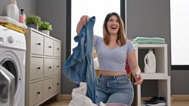 Junge Blonde Frau Lächelt Selbstbewusst Und Wirft Kleider Waschküche — Stockvideo