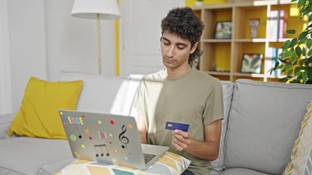 Jovem Hispânico Homem Compras Com Laptop Cartão Crédito Sentado Sofá — Vídeo de Stock