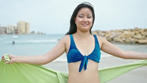年轻的中国妇女穿着比基尼和毛巾在海滩上自信地微笑着 — 图库视频影像