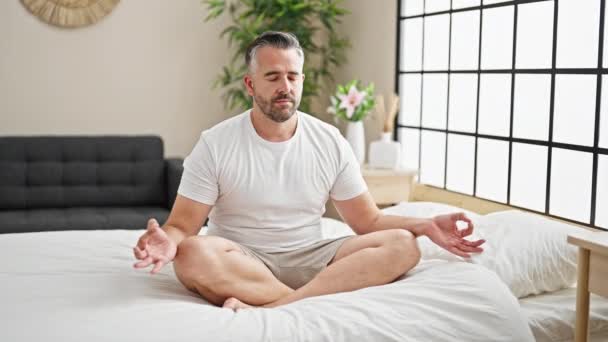 头发灰白的男人坐在床上做瑜伽练习 — 图库视频影像