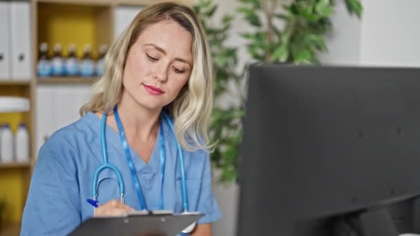 年轻的金发女医生在诊所用电脑写医疗报告 — 图库视频影像