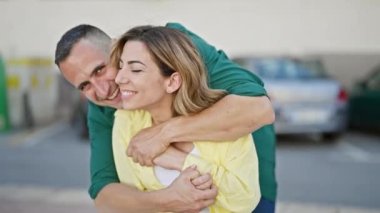 Man and woman couple hugging each other kissing at street