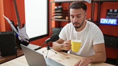 Genç Arap adam müzik muhabiri radyo programında konuşuyor. Kahve radyo stüdyosu içiyor.