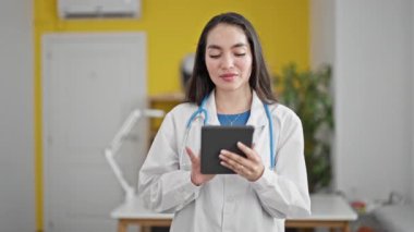 Genç, güzel İspanyol kadın doktor. Klinikte dokunmatik ped kullanarak gülümsüyor.