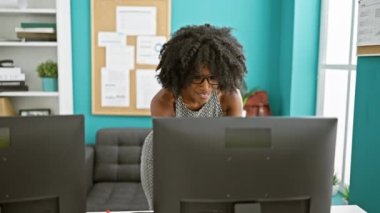 Ofiste kutlayan bilgisayar kullanan Afrikalı Amerikalı iş kadını.