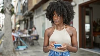 Sokakta akıllı telefon kullanan Afro-Amerikalı kadın.