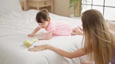 Anne ve kızı yatak odasında dinozor oyuncağıyla oynuyorlar.