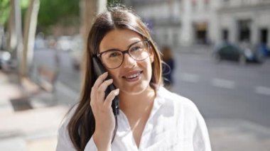 Genç ve güzel İspanyol kadın gülümsüyor. Madrid sokaklarında telefonda mutlu bir şekilde konuşuyor.