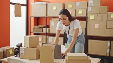 Afro-Amerikalı kadın ekommerans işçisi ofisteki dizüstü bilgisayarı kullanarak gülümsüyor.