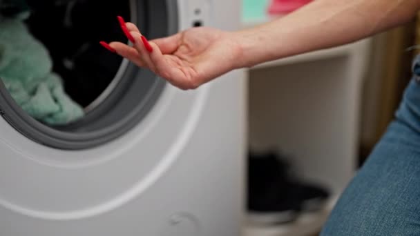 洗濯室で洗濯機に洗剤袋を挿入する若い金髪の女性 — ストック動画