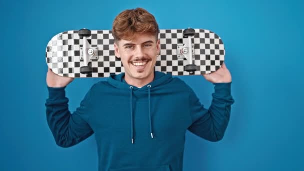 Jonge Latino Man Glimlachen Zelfverzekerd Houden Skate Geïsoleerde Blauwe Achtergrond — Stockvideo
